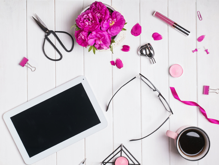 Tablet, coffee, bright pink roses and other small objects on white wooden background, top viewの写真素材