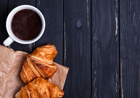 Croissants and coffee on blck wooden table, top viewの写真素材
