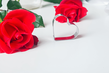 Red roses and heart shape metal mold on the white backgorund. Valentine's day conceptの写真素材