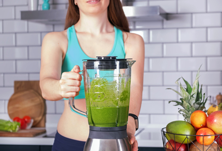 Woman making green smoothie on the kitchenの写真素材