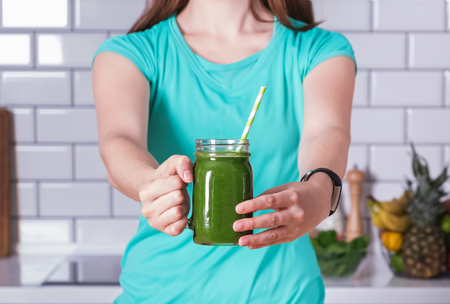 Close up photo of womans hands holding the glass of green smootの写真素材