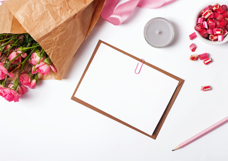 Blank paper, candle and roses on the white background, top viewの写真素材
