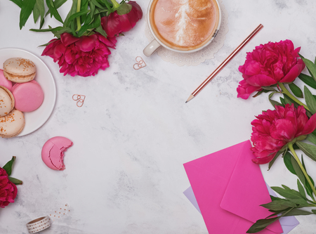 Coffee, pink peonies and macarons on the marble background, top view.の写真素材