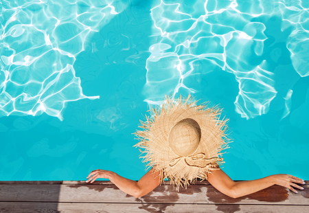 Woman in big straw hat sitting in the swimming poolの写真素材