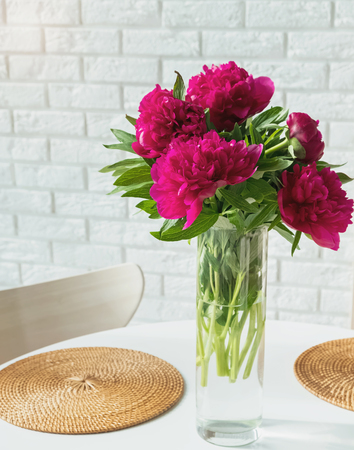 Pink peonies in a glass vase standing on the table.の写真素材