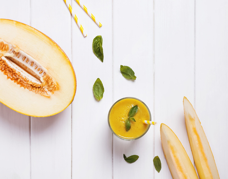 Refreshing melon smoothie with basil on the white wooden table top viewの写真素材