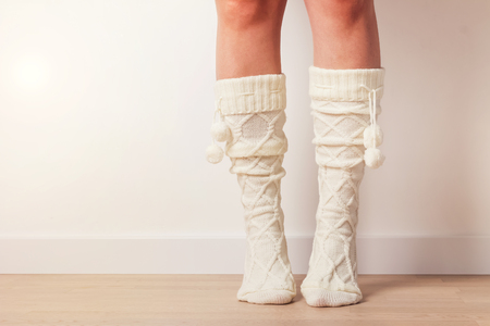 Woman's feet in warm knitted socks standing on toes at home. Close-up shot.の写真素材