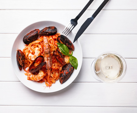 Seafood pasta with shrimps and mussels and a glass of white wineの写真素材