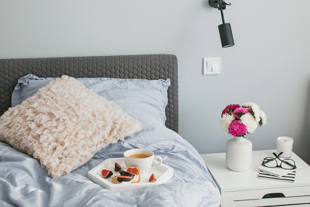 Tray with coffee and fig toast standing on the bed.の写真素材