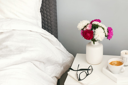 Part of bedroom in the morning with flowers and coffee on the nightstandの写真素材