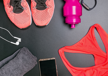 Fitness accessories including sneskers, top, bottle with water on black backgroundの写真素材
