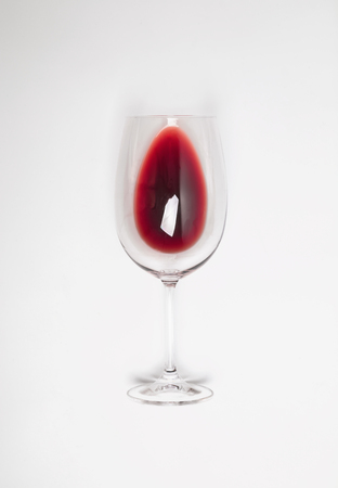 Glass with poured red wine lying on the white backgroundの写真素材
