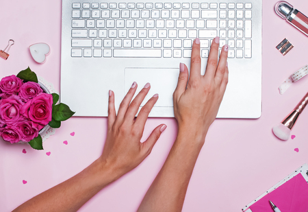 Womans hands typing on the laptop standing on pink background.の写真素材