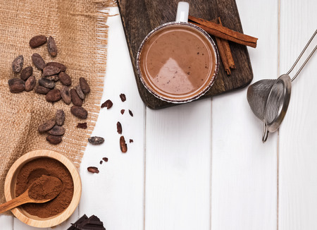 Hot chocolate in the cup, cocoa beans and powder on the white wooden tableの写真素材