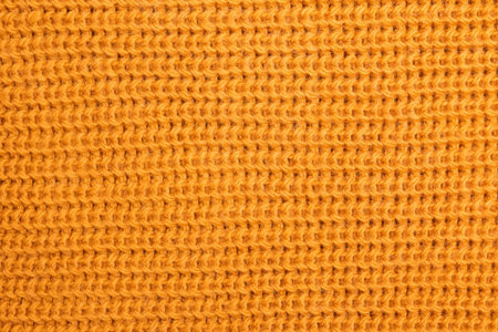 Woolen knitted texture of bright yellow or mustard color close-up