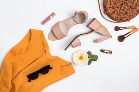 Feminine stylish summer outfit with sandals, straw hat and bag on the white table,の写真素材