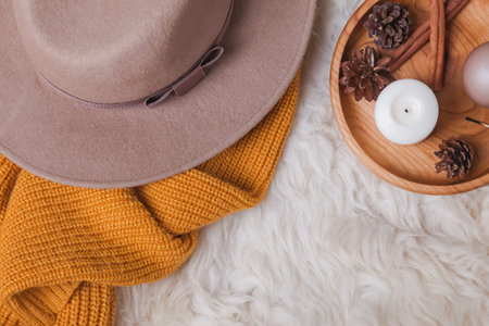 Creative autumn composition with hat, yellow sweater and candles