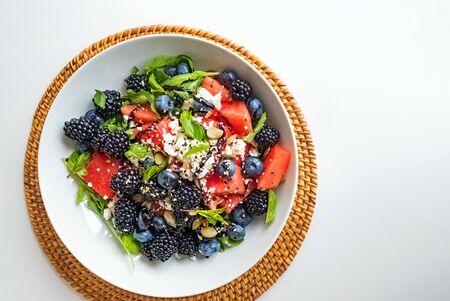 Summer salad with feta, watermelon, berries and balsamic vinegar dressing in a white plateの写真素材