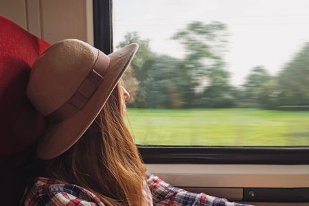 Young woman traveller in felt hat sitting in the moving train