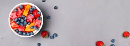 Banner or panorama with fruits and berries in the bowl on the grey backgroundの写真素材