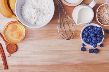 Ingredients for blueberry muffins preparation on wooden table, top view.の写真素材