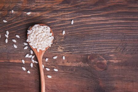 Uncooked rice in the wooden spoon top view.の写真素材