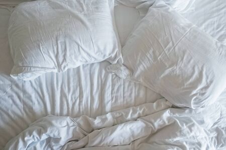 Empty bed with disheveled pillows and sheetsの写真素材