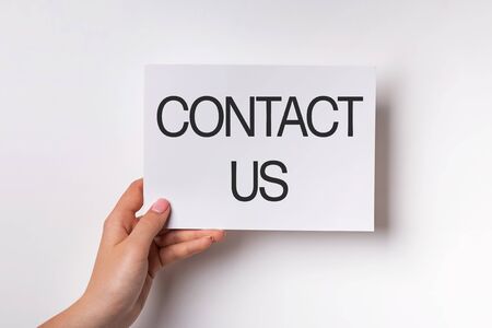 Womans hand holding a card with text Contact Usの写真素材