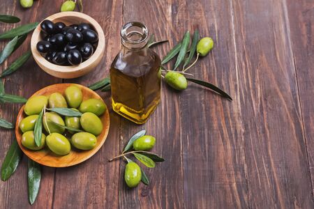 An olive oil in the bottle and some olives and branches on the wooden tableの写真素材