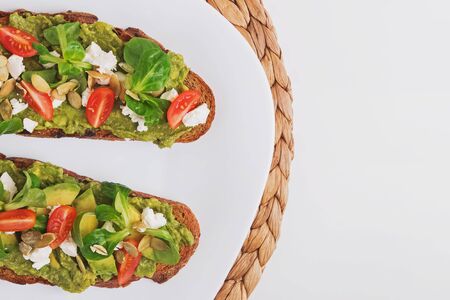 Two rye bread toasts with mashed avocado, tomatoes and feta cheeseの写真素材