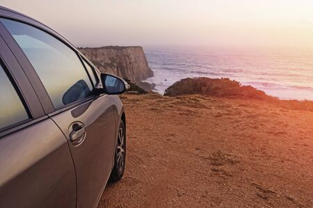 Close-up shot of the car standing with the view to the ocean on sunset.の写真素材