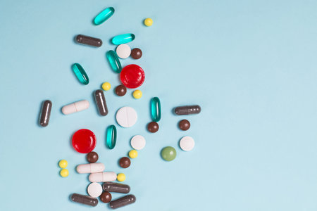 Different multi colored pills and tablets on blue background.