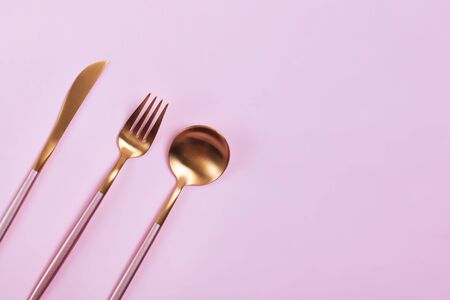 Elegant golden cutlery on pink background, top viewの写真素材