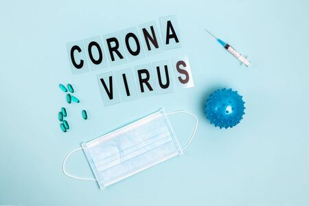 Abstract virus strain model of Coronavirus disease COVID-19, pills, syringe and mask on blue with copy space.の写真素材
