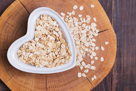 Oatmeal in heart-shaped plate on wooden surface