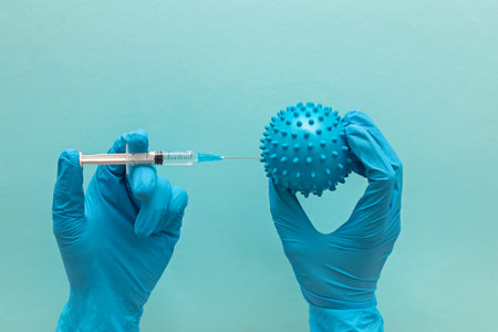 Hand in medical glove holds syringe and abstract virus model
