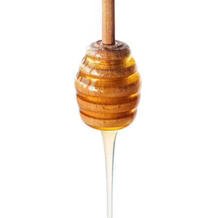 Honey dripping from a wooden dipper isolated on a white background close-upの写真素材