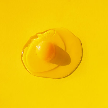 Raw egg on yellow background, top view. Creative minimal concept