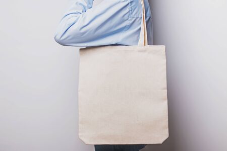 Girl in blue shirt holds blank cotton eco tote bag, design mockup.の写真素材