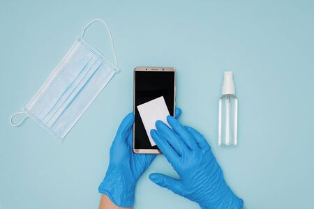 Hands wearing protective gloves cleaning and desinfecting mobile phoneの写真素材