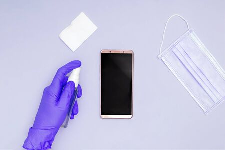 Hands wearing protective gloves cleaning and desinfecting mobile phone for Covid-19 coronavirus disease prevention.の写真素材