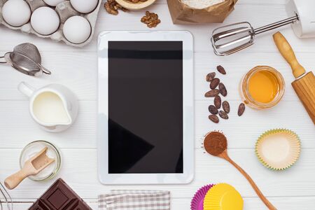 Ingredients and tools for baking and tablet with blank screen and place for text or image on white table. recipe, cookbook, cooking courses online templateの写真素材