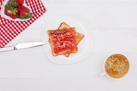Strawberries, toast with strawberry jam and coffee on the white table. Delicious breakfast, top viewの写真素材