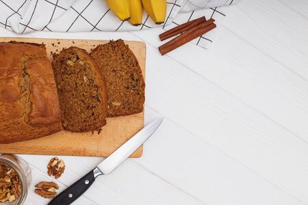 Freshly baked delicious homemade banana bread with walnuts on white wooden table . Flat lay with copy spaceの写真素材