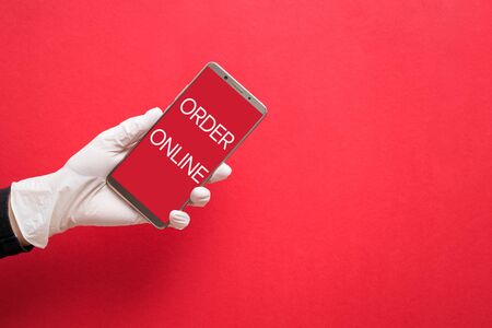 Hand in white protective glove holding smartphone with text Order Onlineの写真素材