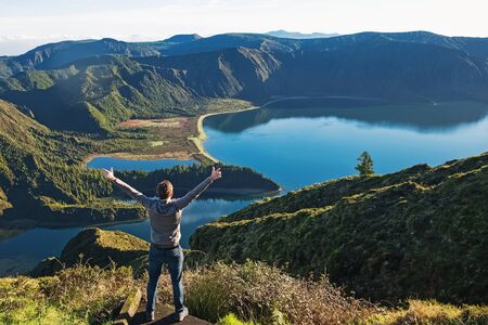 Man traveller standing with the view to the mountain lakeの写真素材