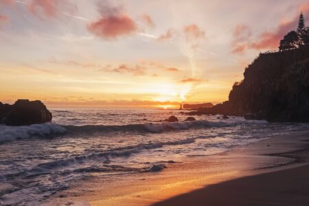 Beautiful sunset on the beach with black volcanic sand in idyllic warm colors.の写真素材