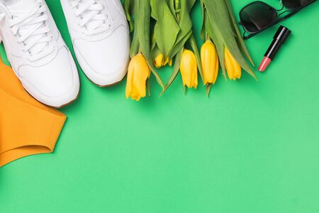 Flat lay composition with feminine accessories and yellow tulips on green background with copy spaceの写真素材