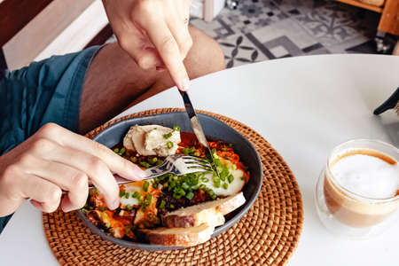 Man eating breakfast with eggs with tomato sauceの写真素材
