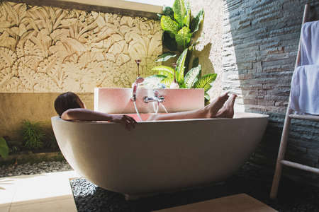 Man lying in bathtub full of flower petals.の写真素材